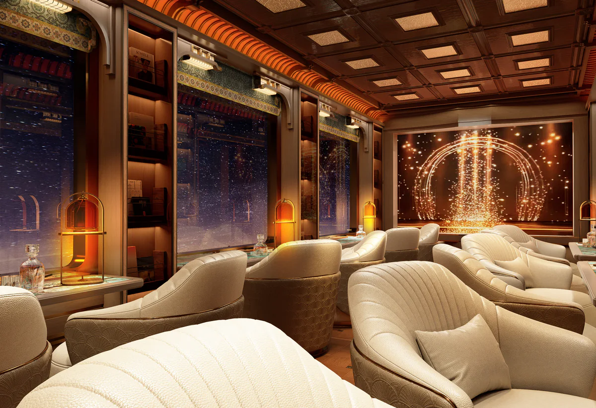 Nighttime design of the Yunque observation lounge with cream armchairs, amber lamps and an illuminated cinema screen.